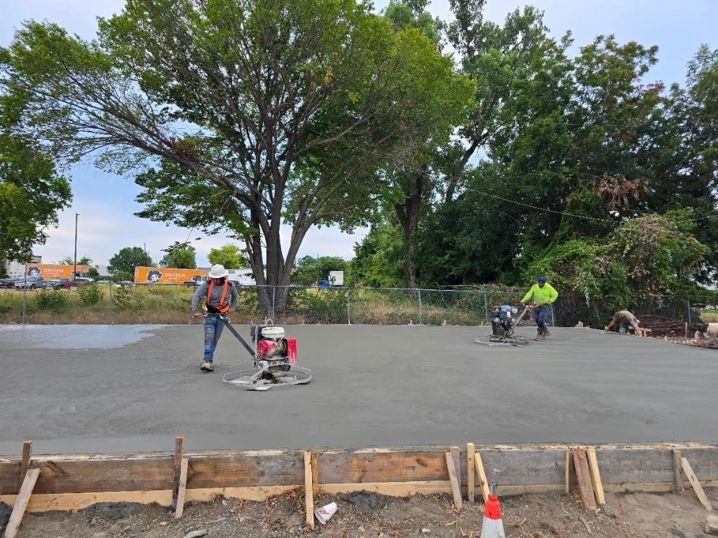 Crew using power trowels to finish large concrete slab